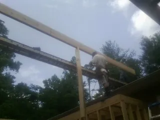 Carpenter setting a ridge beam over a new addition frame — Ice Dam Removal by Roofing Brothers in Terra Alta