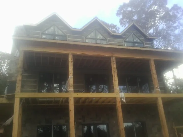 Dormers and porch framing on a large log home under construction — Roof Coating work by our crew in Terra Alta