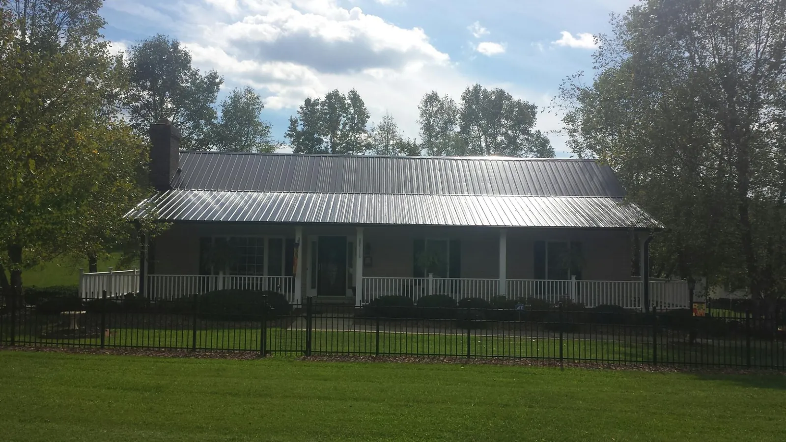 Gray metal roof on a brick ranch with a full width front porch — Gutter Guard Installation work by our crew in Terra Alta