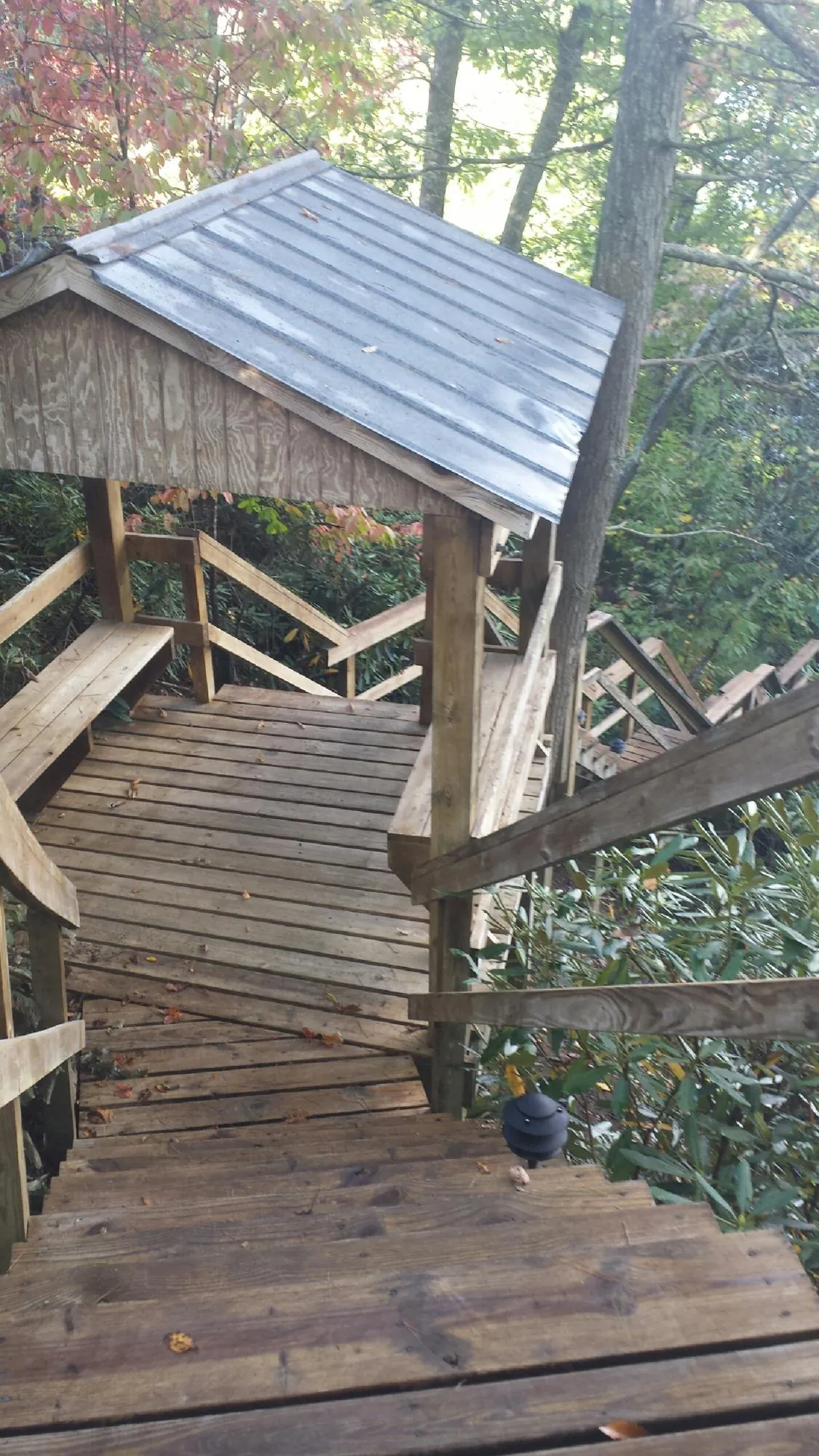 Metal roofed shelter over wooden steps on a wooded walkway — Skylight Repair & Installation work by our crew in Terra Alta