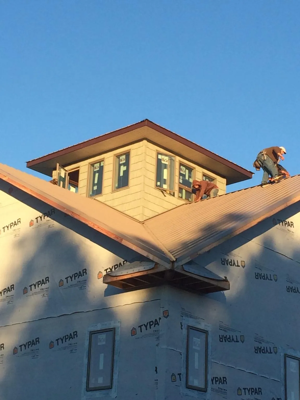 Roofers working around a rooftop cupola on a new metal roof at sunset — Roof Waterproofing in Terra Alta by Roofing Brothers